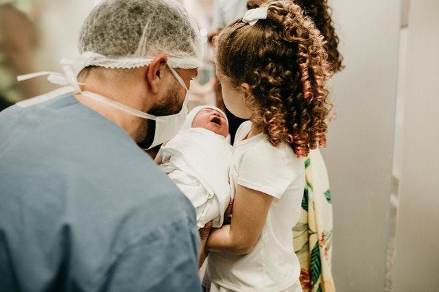 Doctor con niño recien nacido y hermana